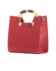 Side of a red ostrich textured handbag on a white background