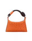 Orange handbag with a knotted handle on a white background