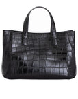 Back of a black crocodile textured handbag on a white background