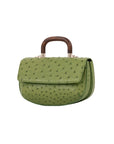 Side of a green ostrich textured handbag with wooden handle on a white background