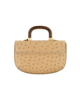 Back of a tan ostrich handbag with a wooden handle on a white background
