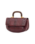 Side of maroon handbag with a wooden handle on a white background