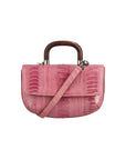 Front of a pink textured handbag with a strap and wooden handle on a white background