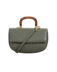 Front of a green ostrich-patterned handbag with a strap and wooden handle on a white background