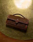 Brown leather clutch bag on a gold surface
