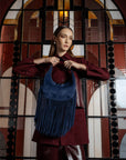 Woman holding a blue suede handbag with fringe design