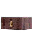 Dark brown ostrich textured watch box with a gold clasp on a white background