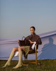 Woman sitting on a chair holding a brown semi suede handbag
