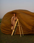 Person standing on a ladder holding a brown suede handbag
