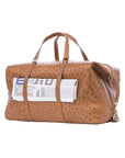 Large brown ostrich bag with straps and a newspaper on a white background
