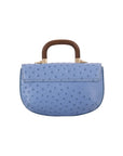 Back of a blue ostrich handbag with a wooden handle on a white background