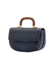 Side of a navy crocodile handbag with a wooden handle on a white background