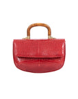 Front of a red crocodile-patterned handbag with a wooden handle on a white background