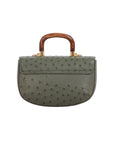 Back of a green ostrich-patterned handbag with a wooden handle on a white background