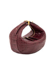 Maroon crocodile-patterned handbag with gold accents on a white background
