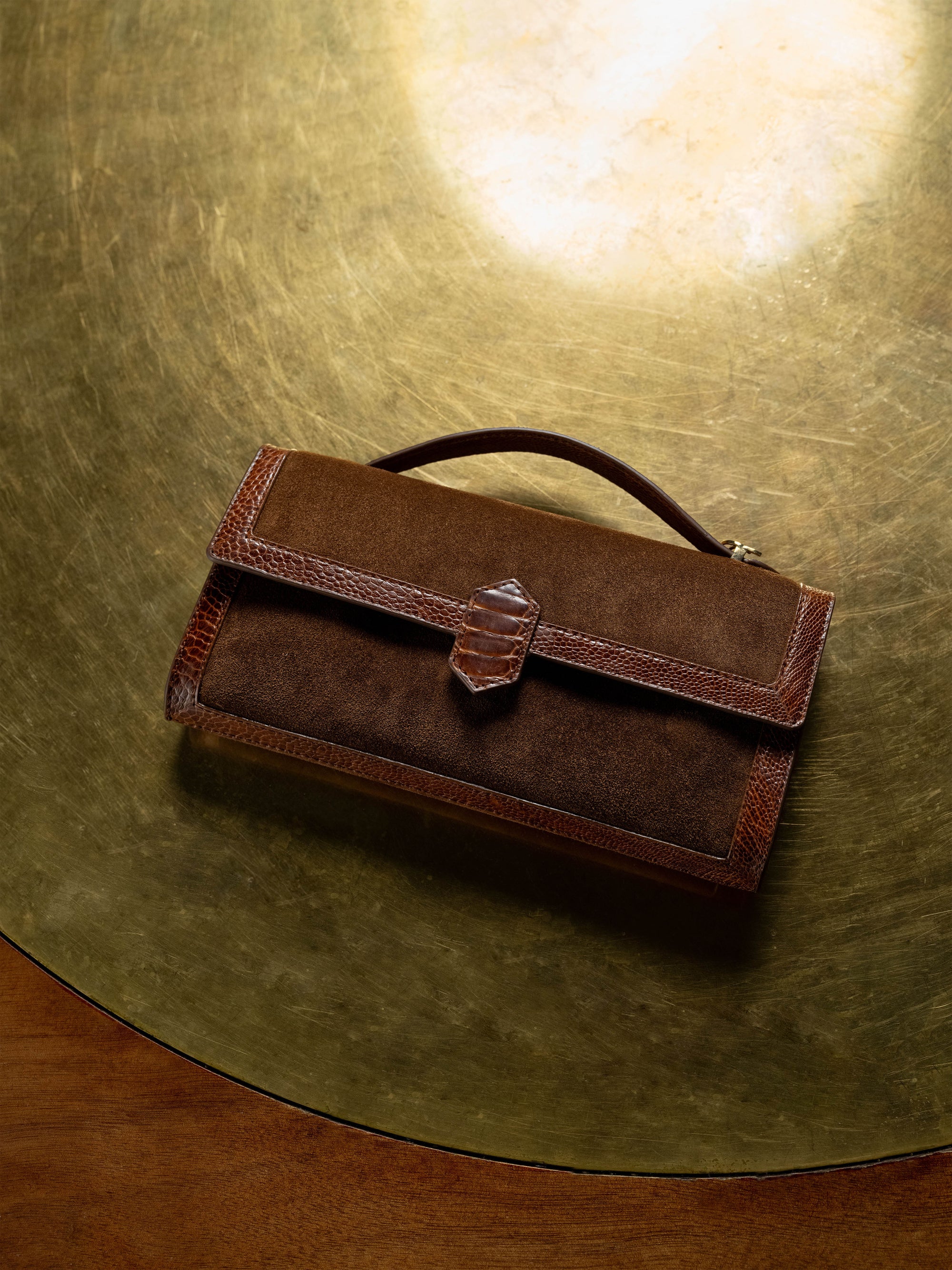 Brown leather clutch bag on a textured gold surface