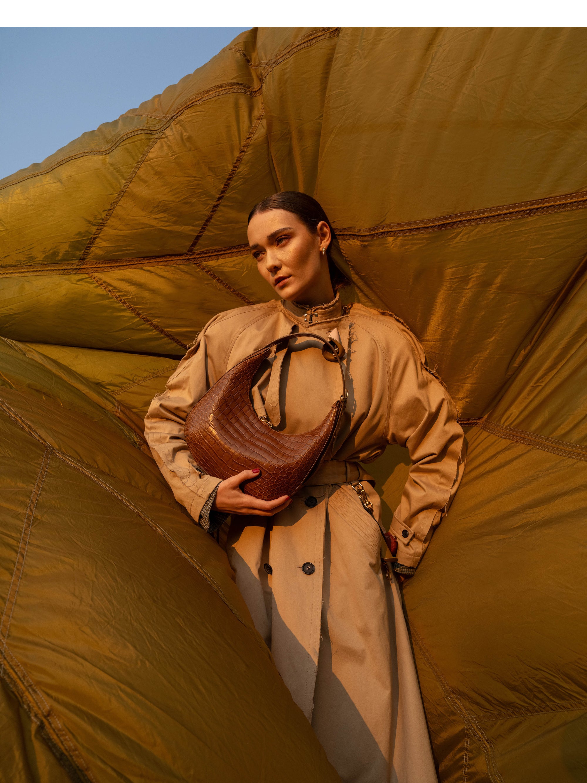 Woman holding a brown crocodile-textured leather bag