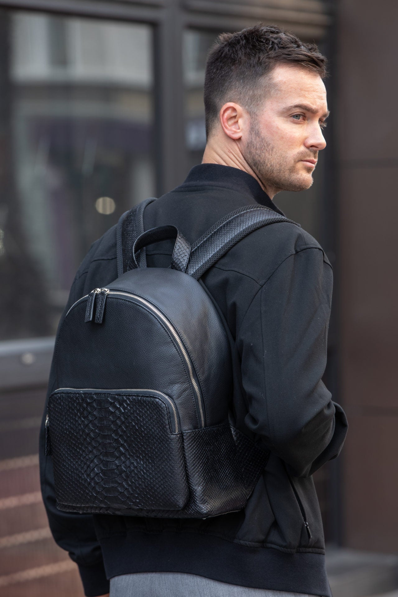 Men wearing a black python textured backpack 