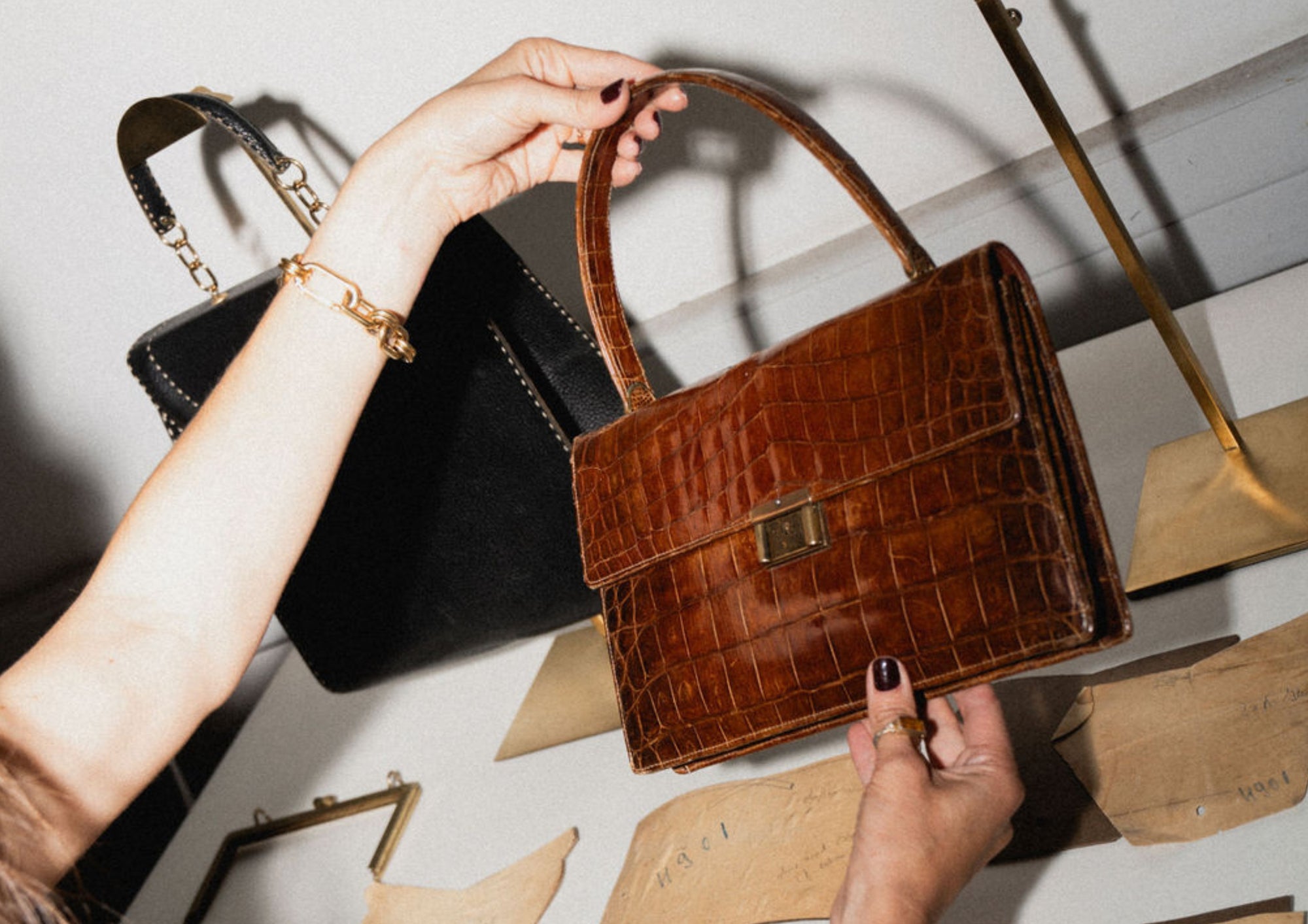 Person holding a brown handbag with a black handbag in the background