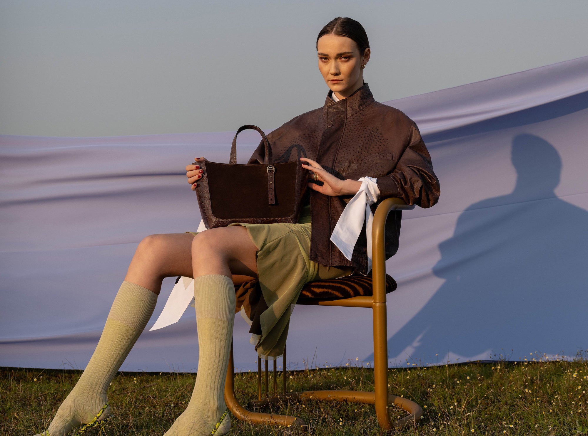 Woman sitting on a chair holding a brown semi suede handbag