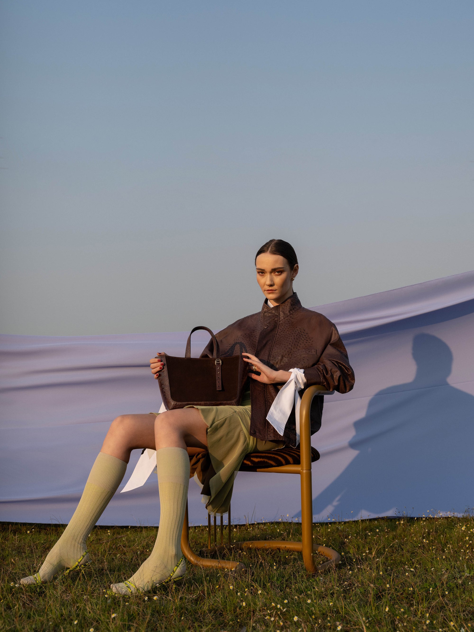 Woman sitting on a chair holding a brown semi suede handbag