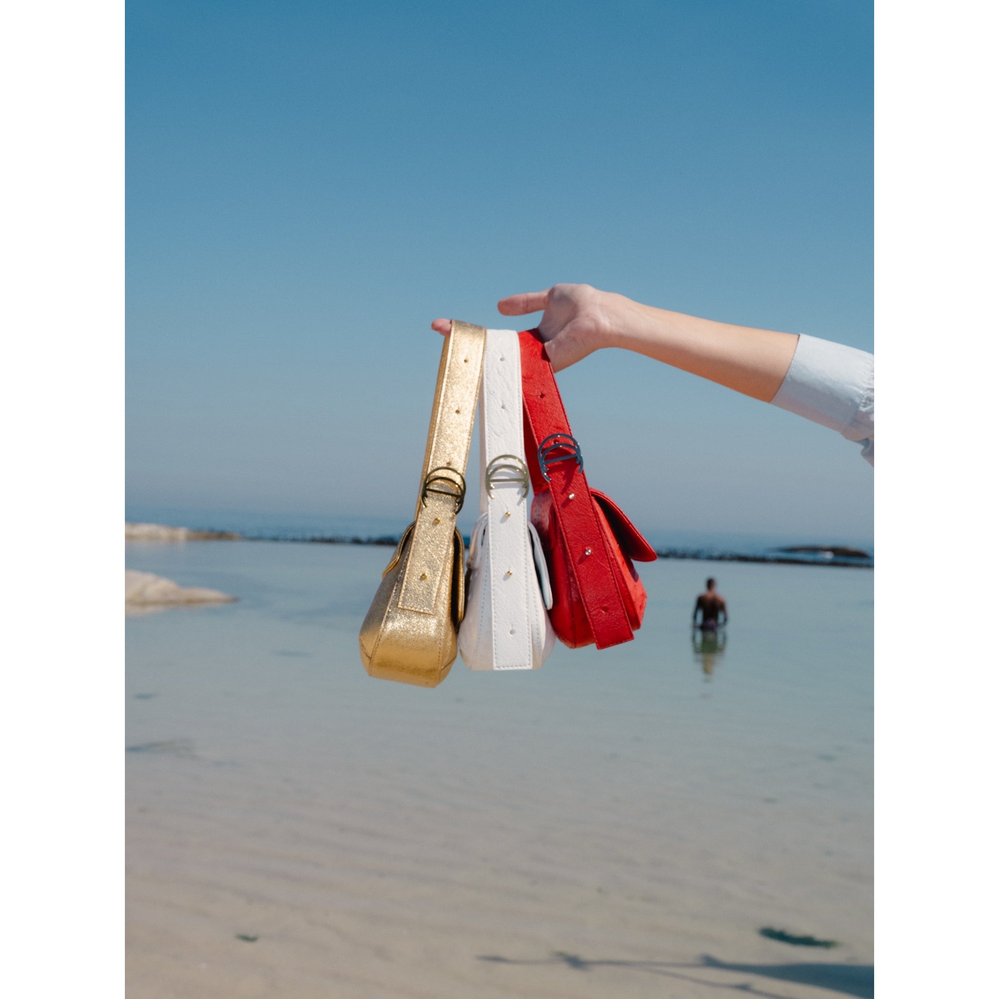 Hand holding 3 various handbags