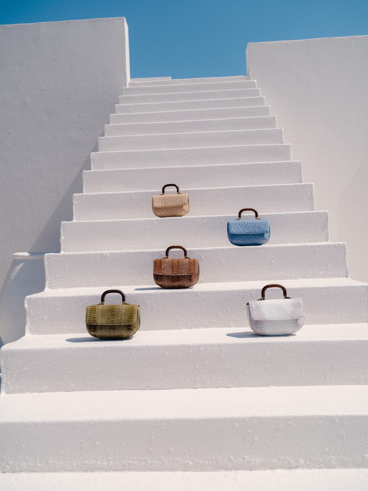 Various colors of handbags with wooden handles on a white staircase