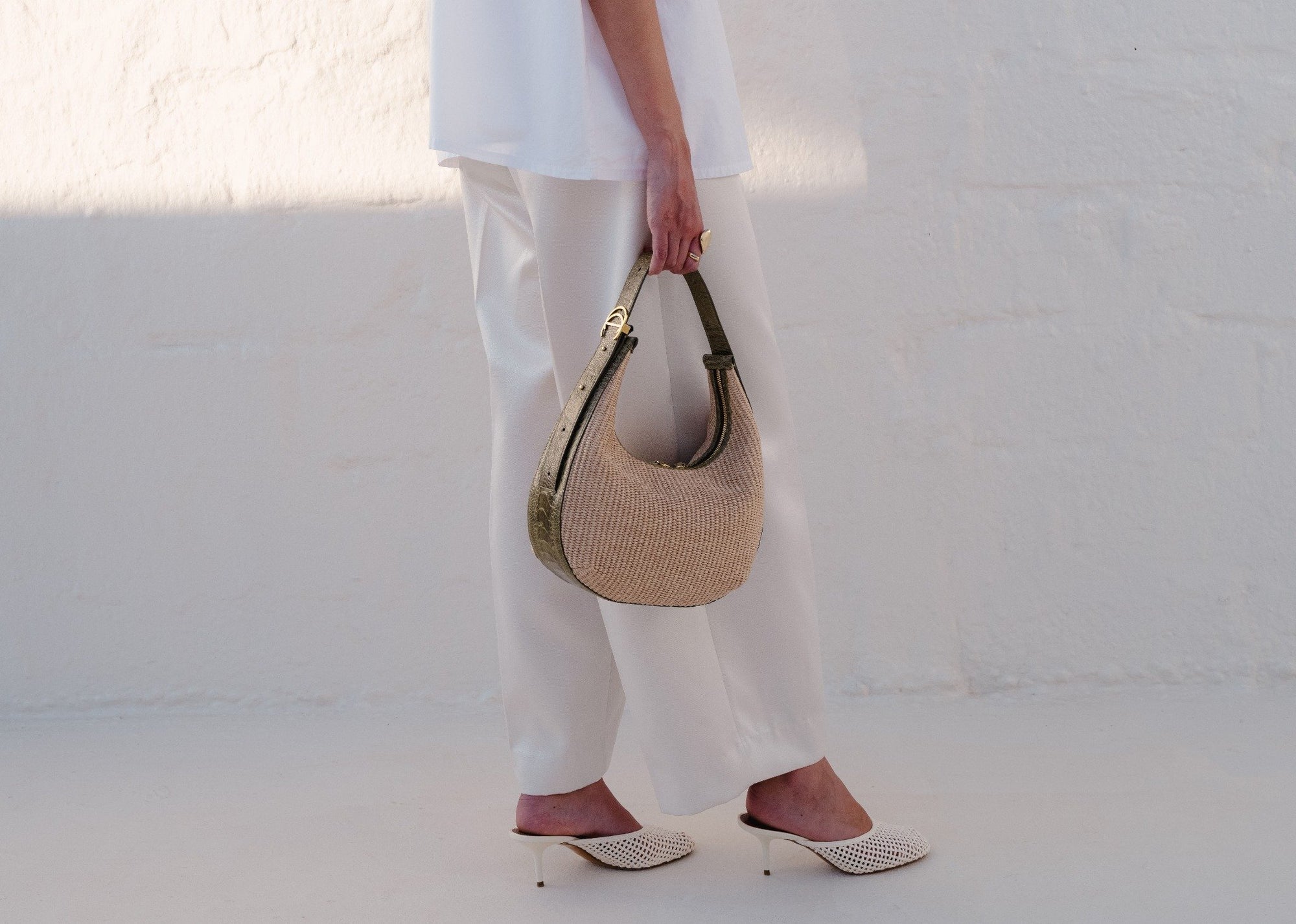 Women wearing white holding a beige handbag on a white background