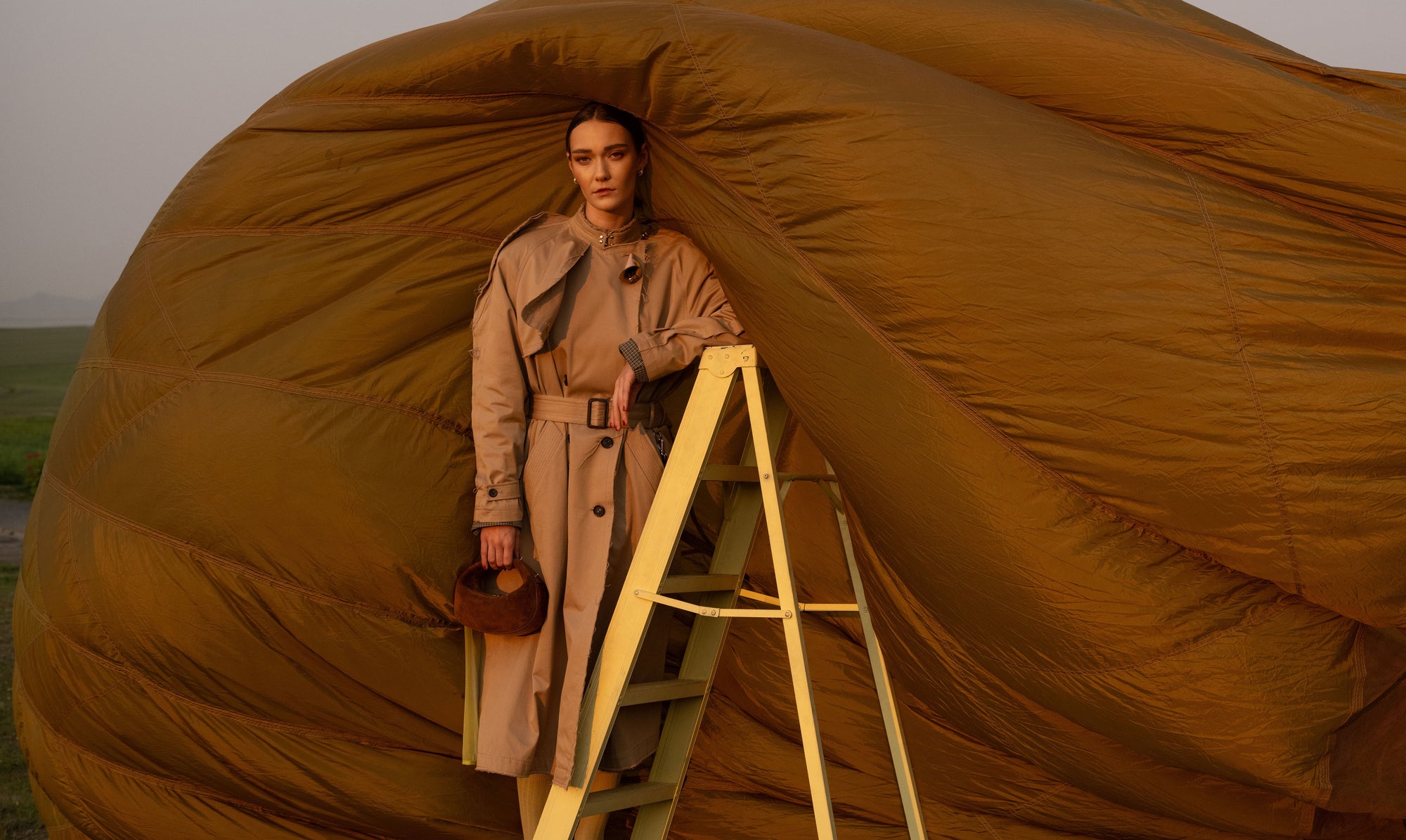 Woman standing on a ladder holding a brown suede handbag
