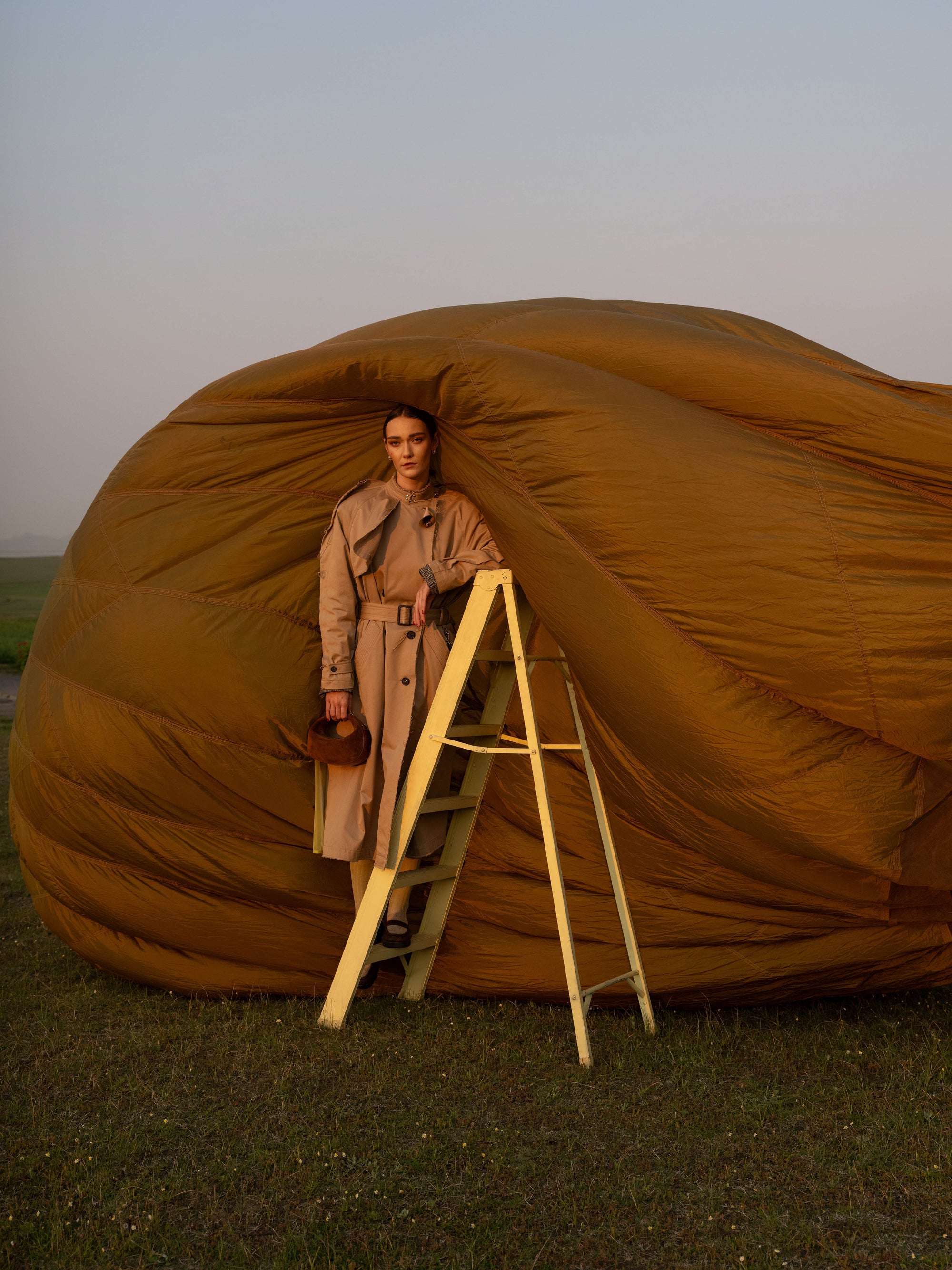 Person standing on a ladder holding a brown suede handbag
