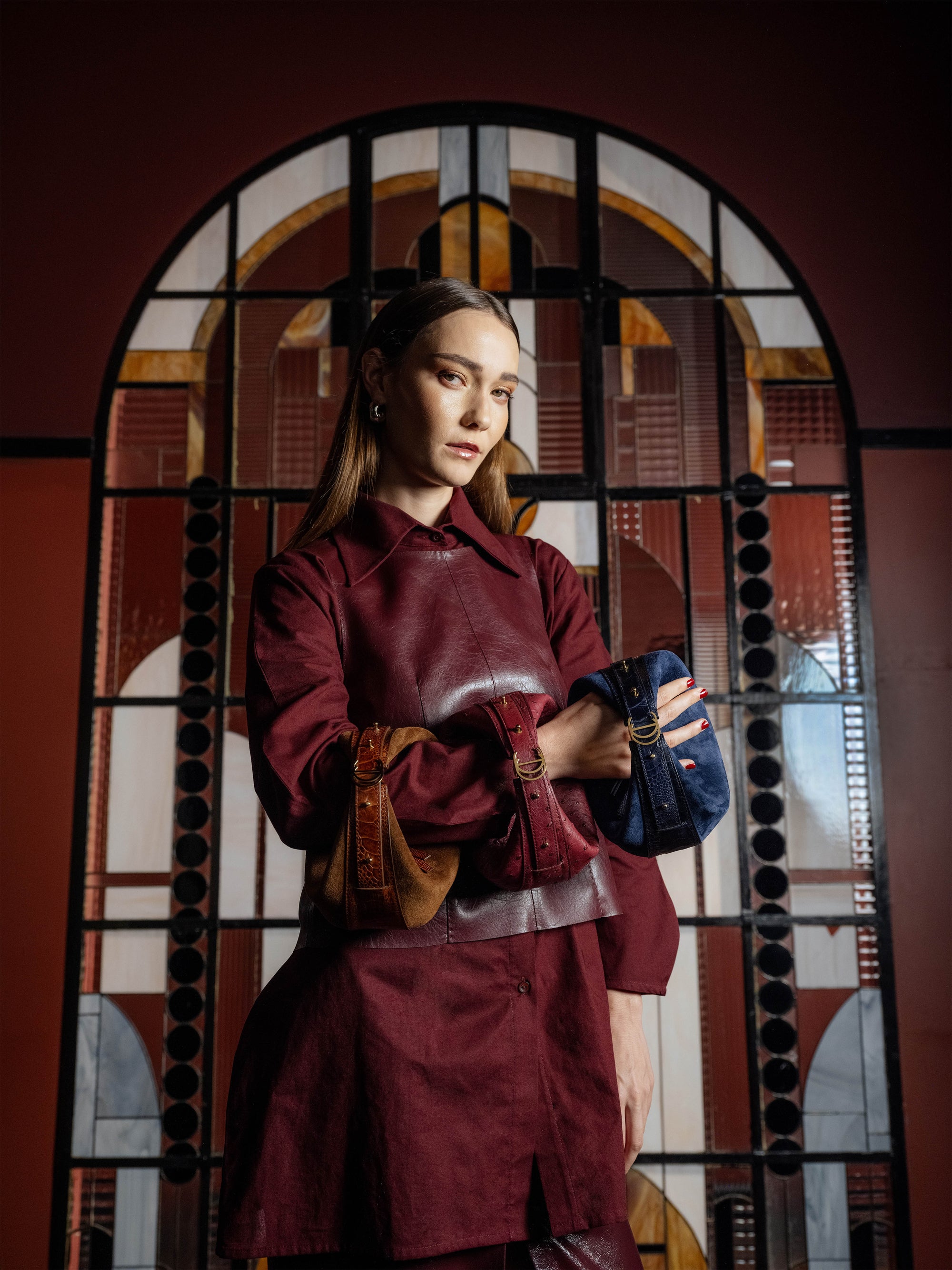 Person wearing a maroon outfit holding various handbags